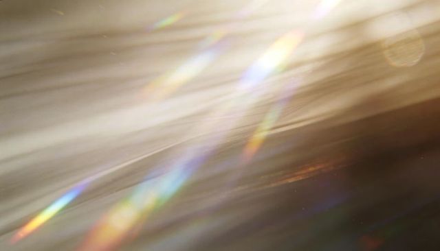 Iridescent prism light streaks shimmering across soft diagonal bokeh flare