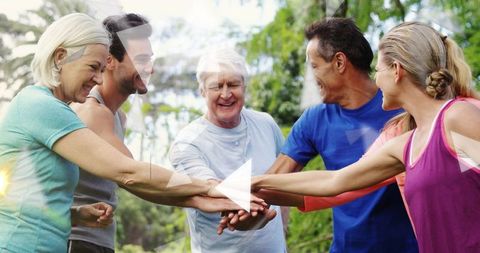 Multigenerational adults together stacking hands outdoors for teamwork fitness and wellness