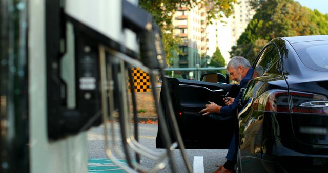 Businessman getting out of car at charging station - Download Free Stock Photos Pikwizard.com