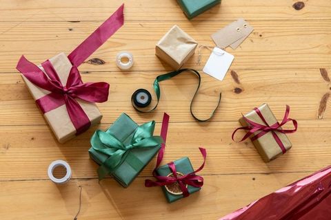 Rustic gift wrapping flatlay with green and burgundy ribbons, kraft tags, tape, twine