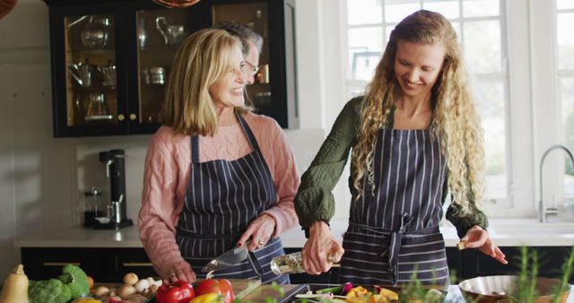 Mother and daughter bonding in a bright kitchen while preparing a meal with fresh vegetables. Ideal for use in articles about family time, healthy meal preparation, lifestyle blogs, parenting tips, and cooking tutorials.