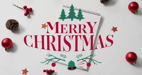 Merry christmas bold typography on spiral notepad flatlay with red baubles & pinecones