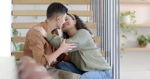 Affectionate Couple Kissing on Wooden Staircase at Home