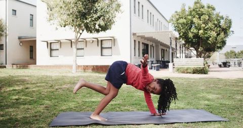 Child Practicing Yoga on Sunny Day in Front of School Building