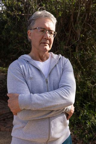 Mature man enjoying nature in grey hoodie among shrubs