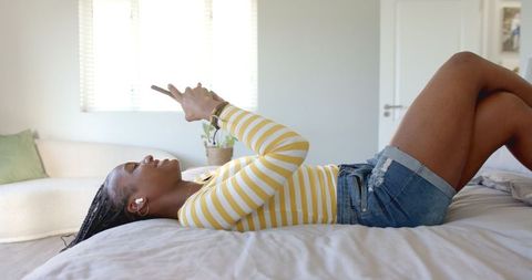 Young Woman Relaxing with Smartphone in Bedroom, Leisure Lifestyle