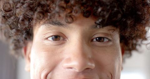 Close-up portrait of youthful person with curly hair smiling