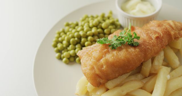 Image of fish, chips and peas on plate with dip. tasty hot homemade fast food meal.