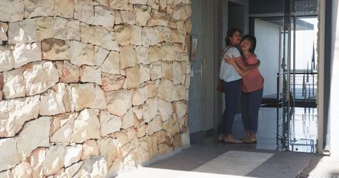 Senior friends embracing in modern home entrance