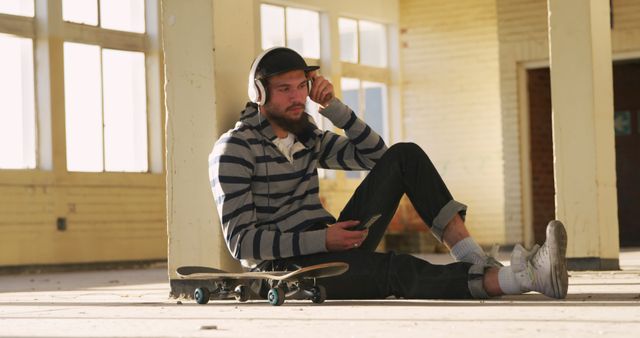 Young Man Relaxing with Headphones and Skateboard in Empty Building - Download Free Stock Images Pikwizard.com