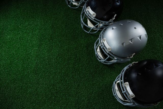 Close-up of American football head gears arranged over artificial turf