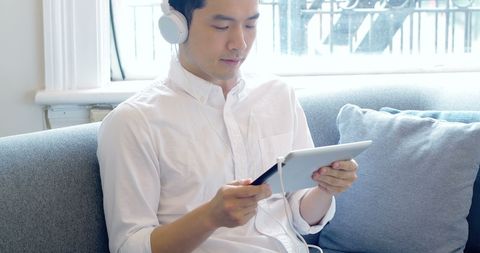 Young Asian Man Enjoying Digital Entertainment on Tablet at Home