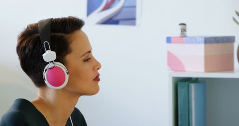 Businesswoman Listening to Music on Headphones in Modern Office