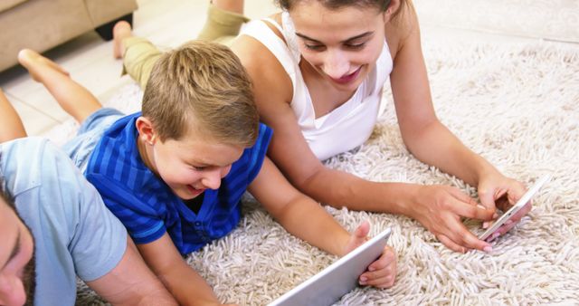 Happy family using tablet and smartphone lying on a carpet at home