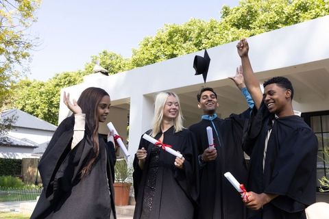 Joyful graduates celebrating with diplomas and mortarboard toss