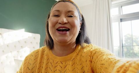 Senior woman smiling with cozy knitted sweater in bright room