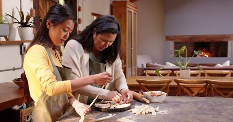 Mother and daughter making lattice pie in cozy kitchen