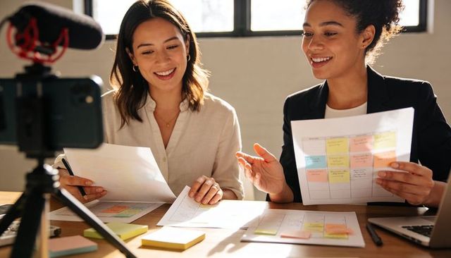 Women planning content calendar with sticky notes and planner while recording livestream