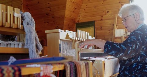 Senior Woman Weaving on Wooden Loom in Artisan Workshop