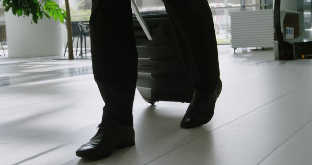 A businessman is captured walking through an office environment, with copy space. His polished black shoes and the briefcase suggest a professional setting and a sense of purpose.