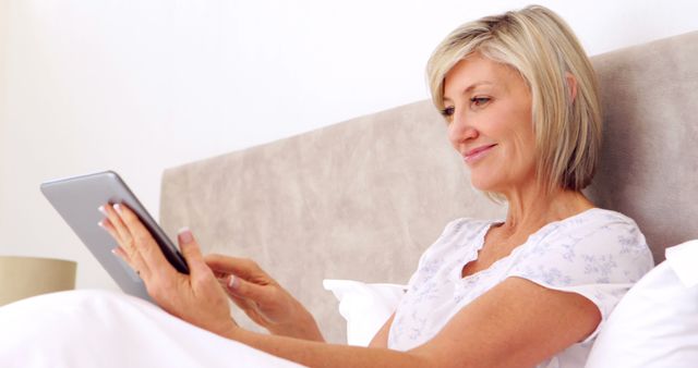 Mature Woman Using Tablet in Bed with Content Smile - Download Free Stock Images Pikwizard.com