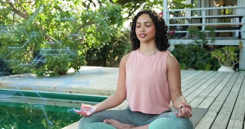 Young woman meditating on wooden deck beside pool with digital wellness circuit overlay