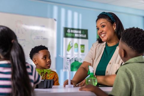 Teaching sustainability with wind turbine model and seedlings smiling african american teacher