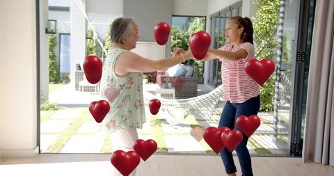 Dancing mother and daughter holding hands surrounded by floating red hearts