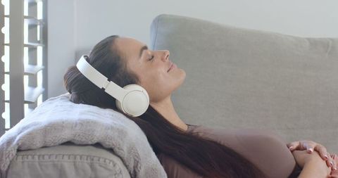 Woman Relaxing with Headphones on Cozy Sofa