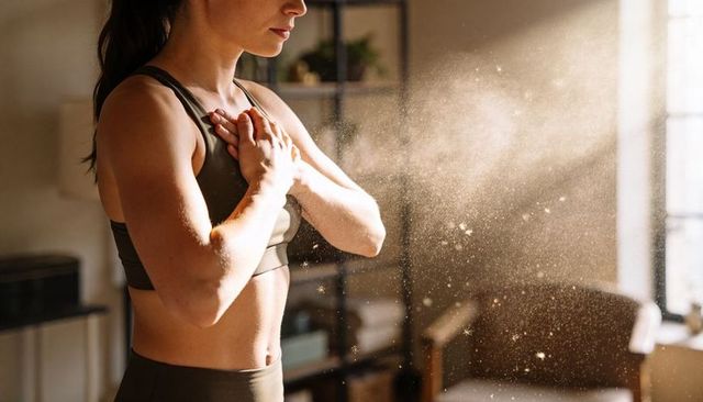 Woman stretching at home gym with hands on chest, sunlit dust particles and calm morning workout