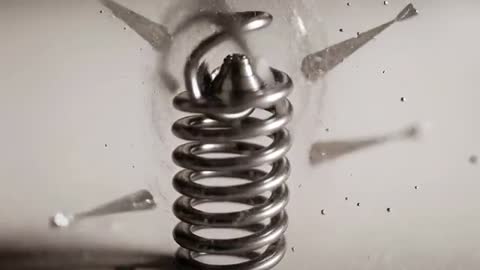 High-Speed Macro Video Showing Droplet Hitting Metal Compression Spring Creating Crown Splash