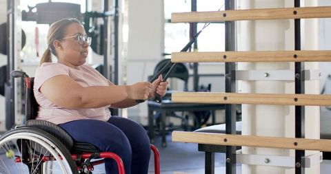 Woman doing rehabilitation exercises with resistance bands in wheelchair