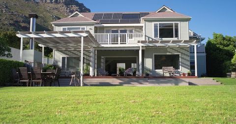 Light-gray two-story house with solar panels, white pergola and spacious backyard deck