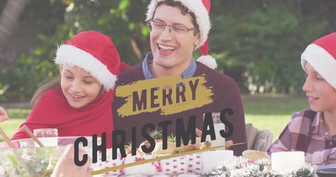 Family in Santa Hats Enjoying Outdoor Christmas Celebration with Greetings Overlay
