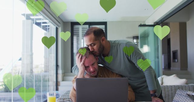 Image of heart icons over diverse gay couple embracing. pride month and celebration concept digitally generated image.