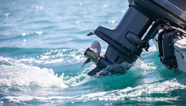 Outboard motor propeller churning turquoise water creating wake and sea foam