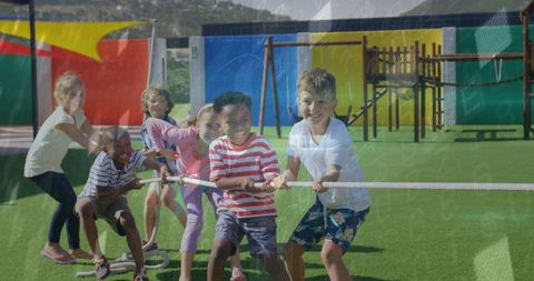 Children Enjoying Tug-of-War Game on Green Field