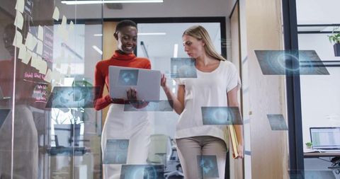 Women collaborating with laptop and holographic ar overlays while walking through office
