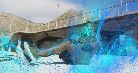Male athlete performing core workout on beach under pier with blue particle water effect
