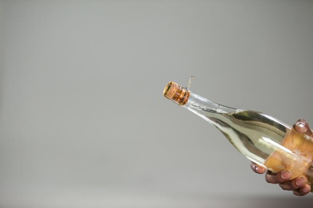 Hand holding champagne bottle against white background