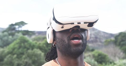 African American man experiencing virtual reality outdoors on sunlit hillside