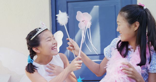 Two Asian girls in playful fairy costumes enjoy a cheerful moment together, with copy space. Their laughter and the whimsical outfits create a joyful and imaginative atmosphere.
