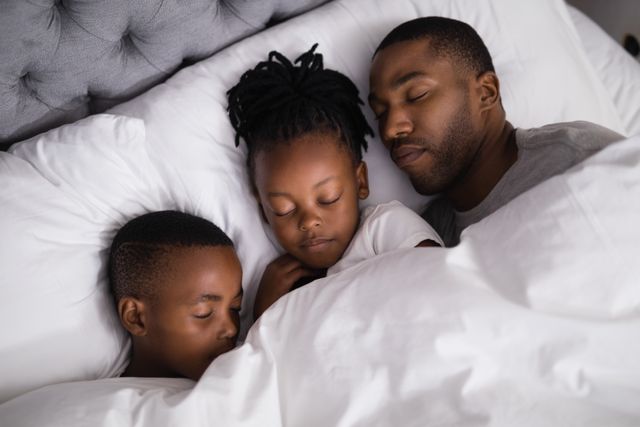High angle view of father with children sleeping together on bed at home