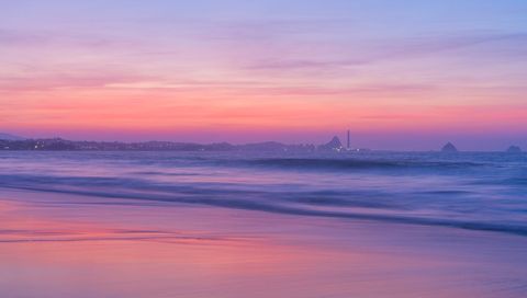 Pastel Sunset Over Calm Ocean, Silhouetted Coastline and Soft Beach Reflections