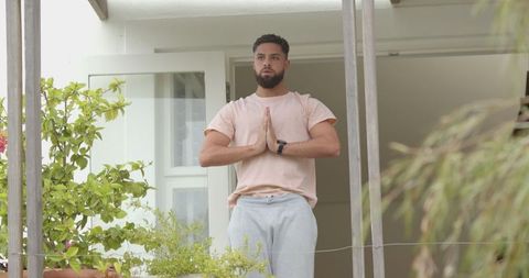 Man Meditating on Urban Balcony With Plants in Relaxation Pose