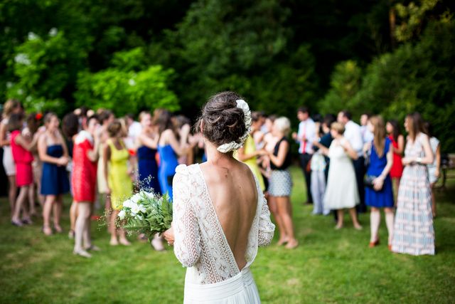 Rear view of bride standing in the garden against people. Wedding and celebration concept