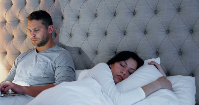 Man Using Laptop in Bed While Partner Sleeping - Download Free Stock Images Pikwizard.com