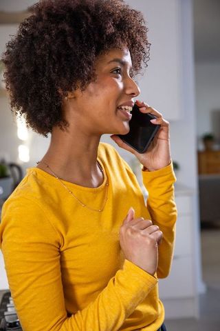 Smiling Woman Holding Smartphone in Modern Kitchen