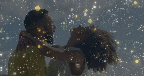 Joyful couple embracing under magical light particles