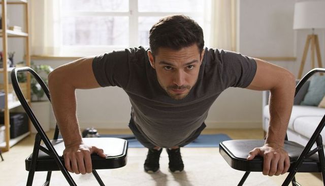 Man performing elevated push-ups using folding chairs in bright minimalist living room